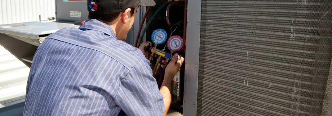HVAC technician servicing a condenser unit in Pace